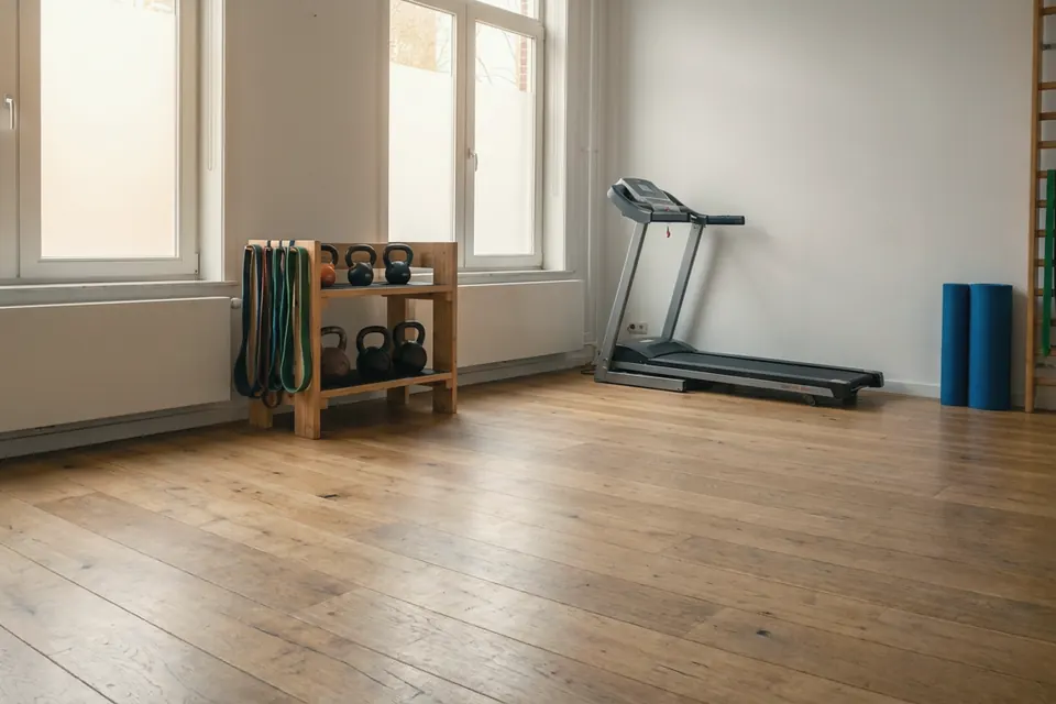 Oefenzaal van de praktijk in Bunnik, met houten vloer, grote ramen, kettlebells en een loopband